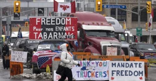 virus-outbreak-canada-protest-woman-crosses-street-front-of-vehicles-parked-of-trucker-protest-640x335